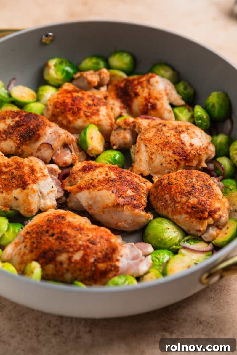 Sheet Pan Golden Chicken and Roasted Brussels Sprouts 7 Chicken thighs and Brussel sprouts being cooked in gray skillet.
