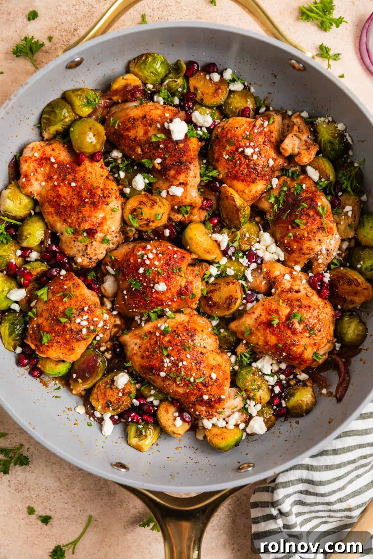 Sheet Pan Golden Chicken and Roasted Brussels Sprouts 9 Overhead view of one pan chicken thighs and vegetables topped with chopped parsley, goat cheese and pomegranate arils.