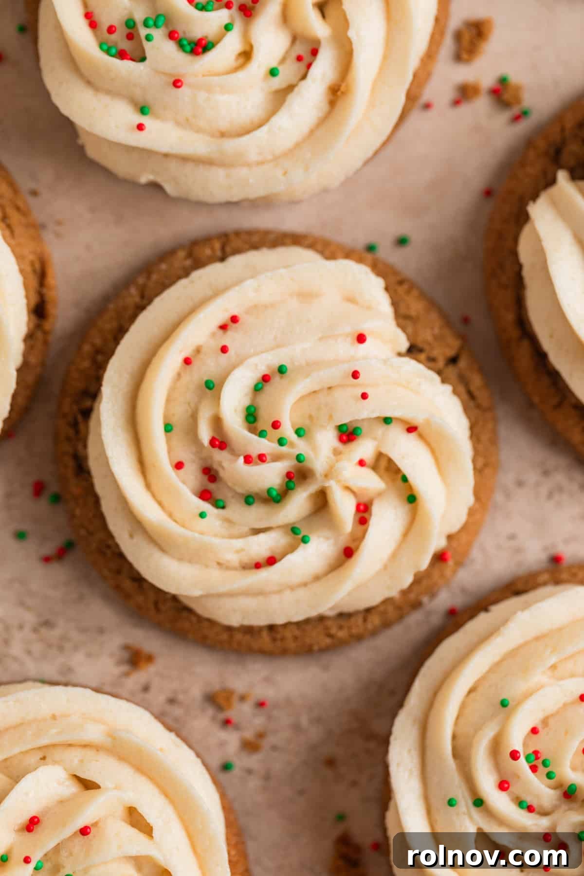 Ginger Cloud Cookies 17 Frosted ginger cookies with sprinkles arranged on surface with cookie crumbs.