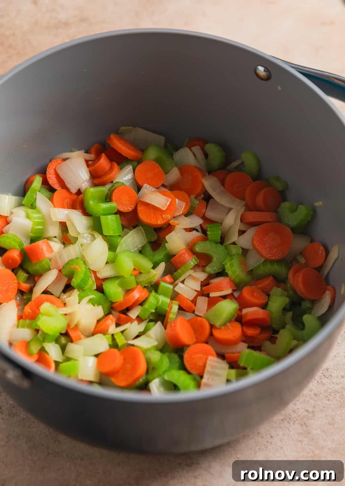 Zesty Lemon Chicken Orzo Soup 3 Chopped celery, onion, and carrots actively sautéing in a large stock pot, forming the aromatic base of the soup.
