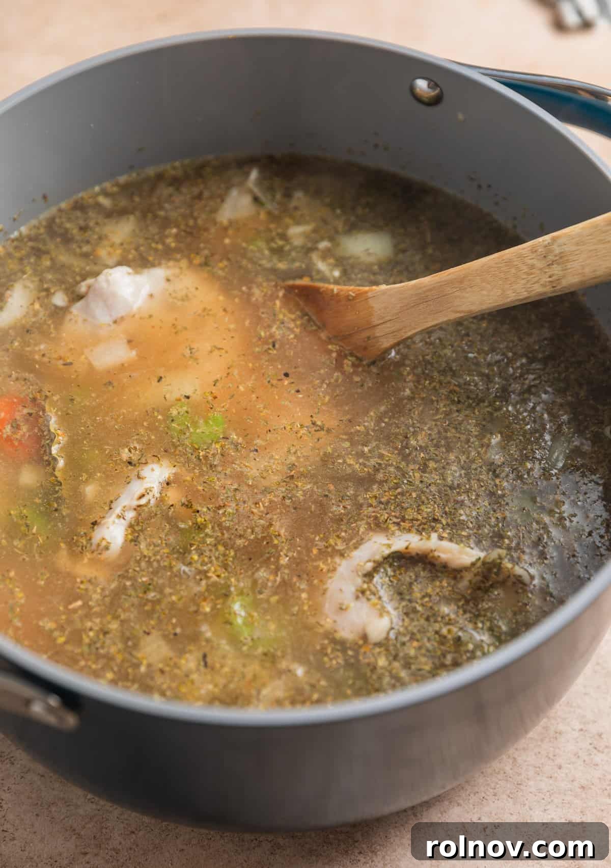 Zesty Lemon Chicken Orzo Soup 4 Uncooked chicken thighs nestled amongst sautéed vegetables in a rich broth, seasoned and ready for simmering.