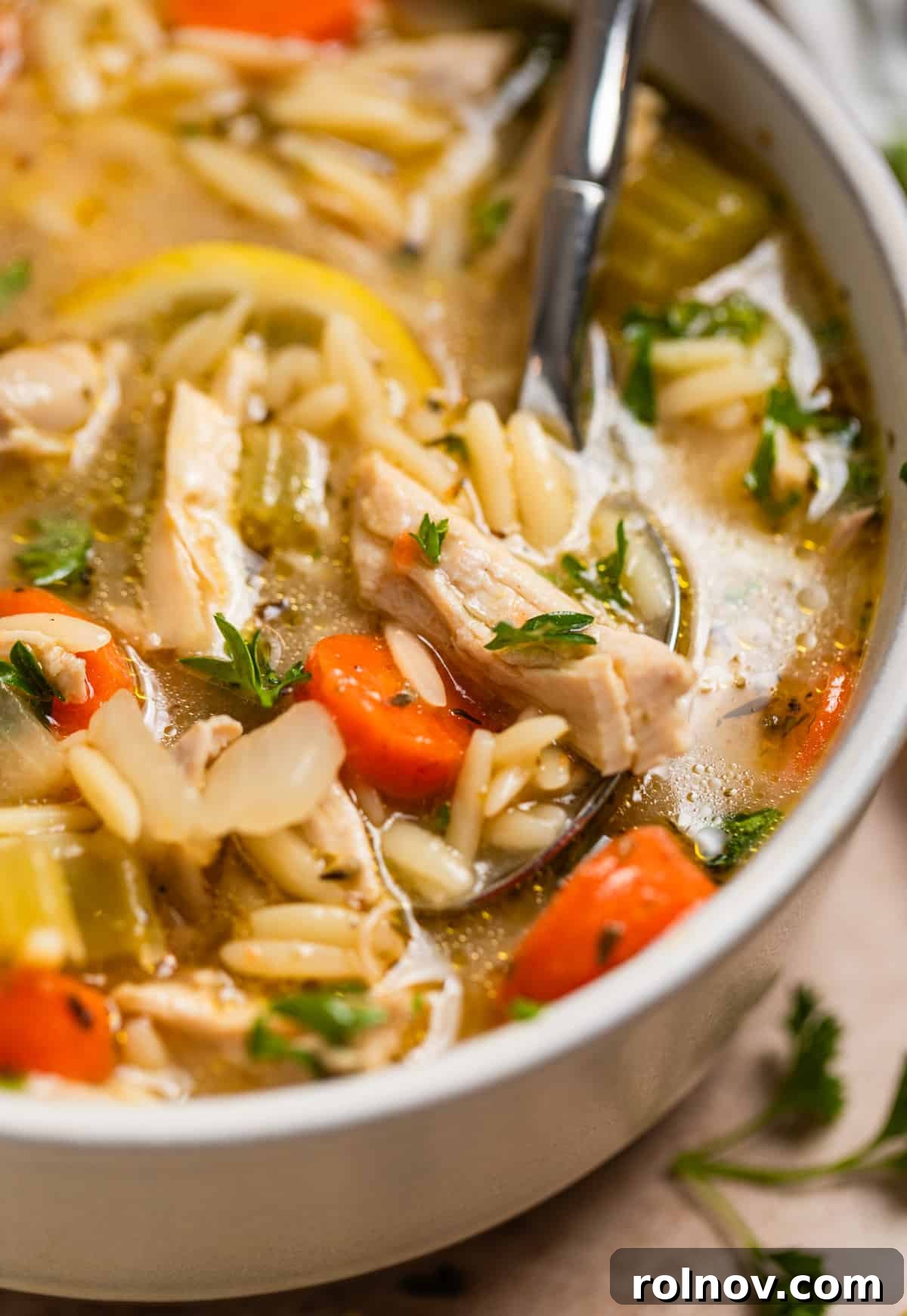 Zesty Lemon Chicken Orzo Soup 8 A close-up shot of a spoonful of hot lemon chicken and orzo soup, ready to be enjoyed.