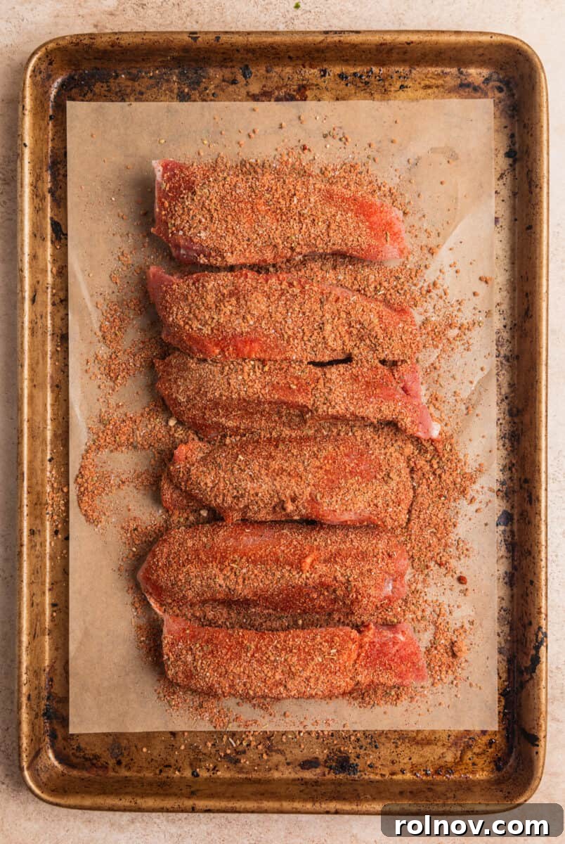 Crispy Air Fryer Country Ribs 6 Country ribs on parchment lined baking sheet with dry rub covering.