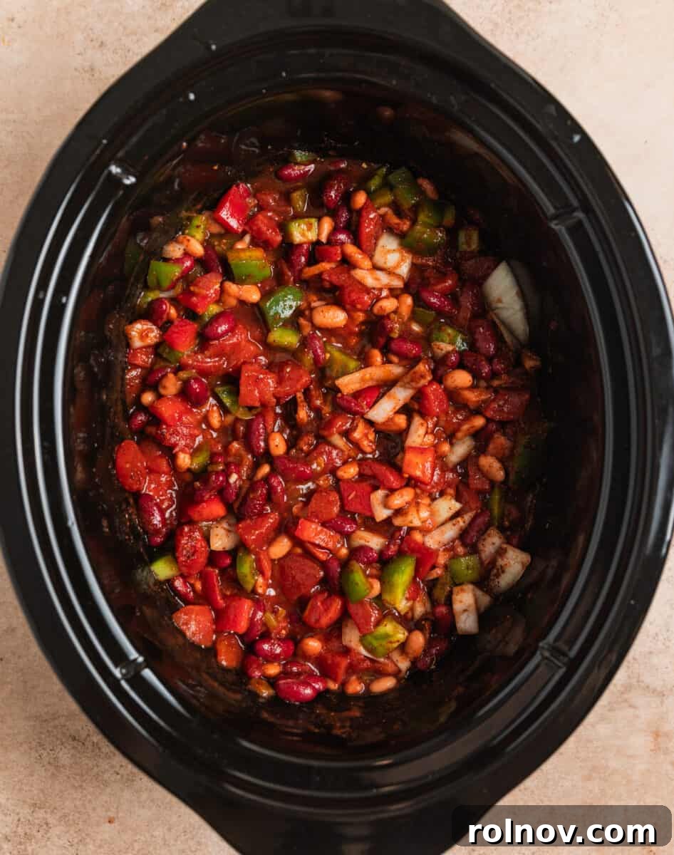 Slow Cooker Pulled Beef Chili 6 Chopped bell peppers, onions, drained beans, an array of spices, and canned tomatoes gathered in a slow cooker, before cooking.