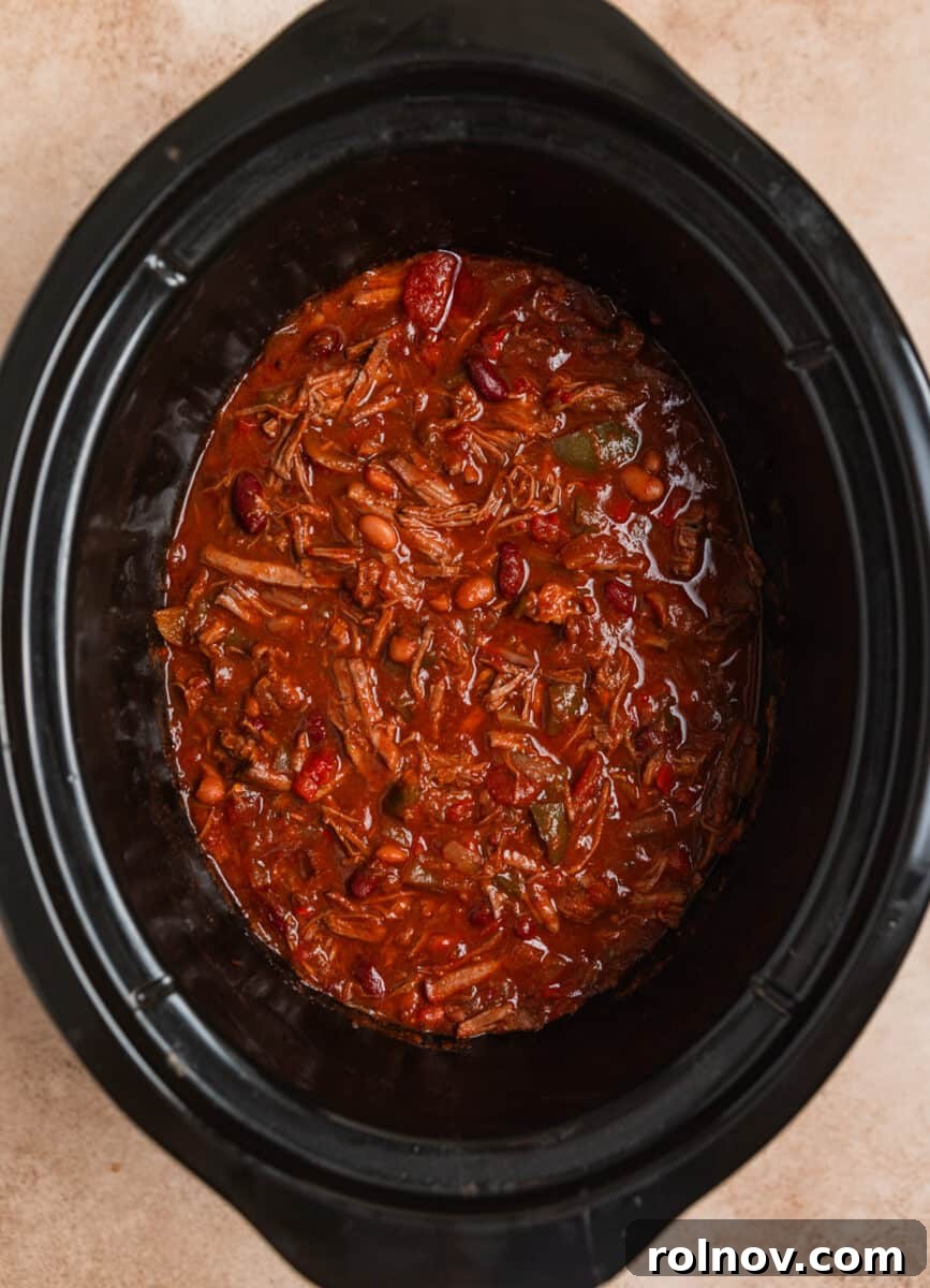 Slow Cooker Pulled Beef Chili 10 Shredded beef chili simmering in the crockpot after the freshly shredded beef has been mixed back into the pot, looking rich and ready.