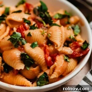 Creamy pasta with tomatoes and spinach topped with chopped fresh basil.