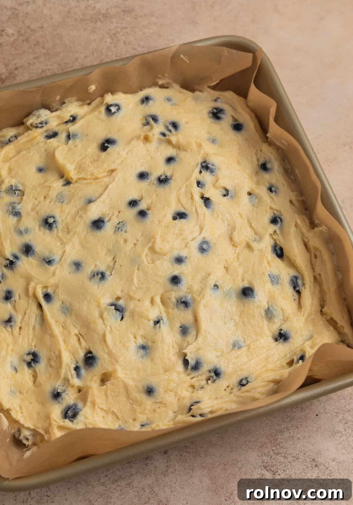 Bright and Zesty Blueberry Lemon Coffee Cake 12 Parchment lined baking pan with lemon blueberry cake batter.