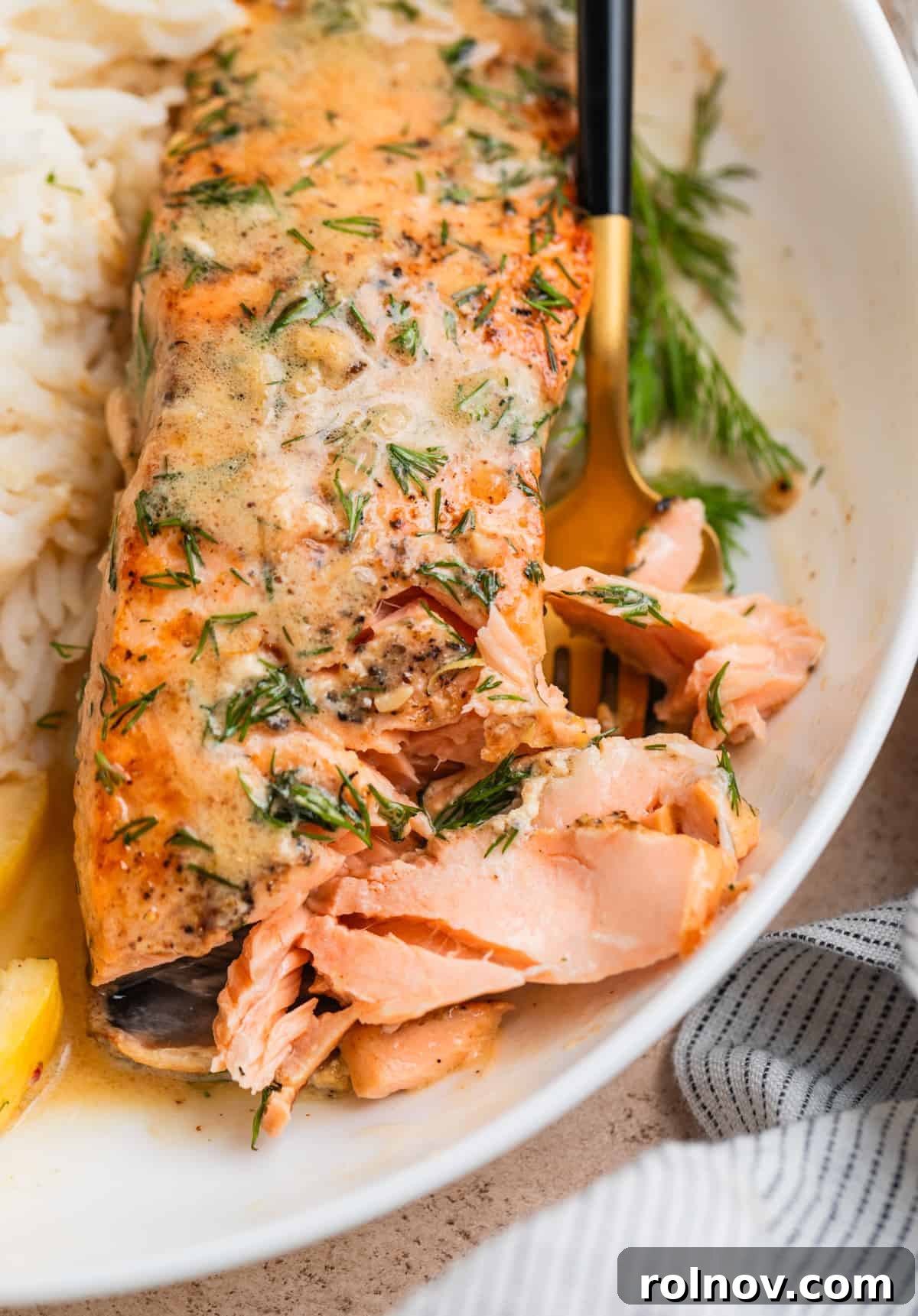 Zesty Lemon Dill Salmon 3 Salmon filet flaked with fork on plate topped with lemon dill butter.