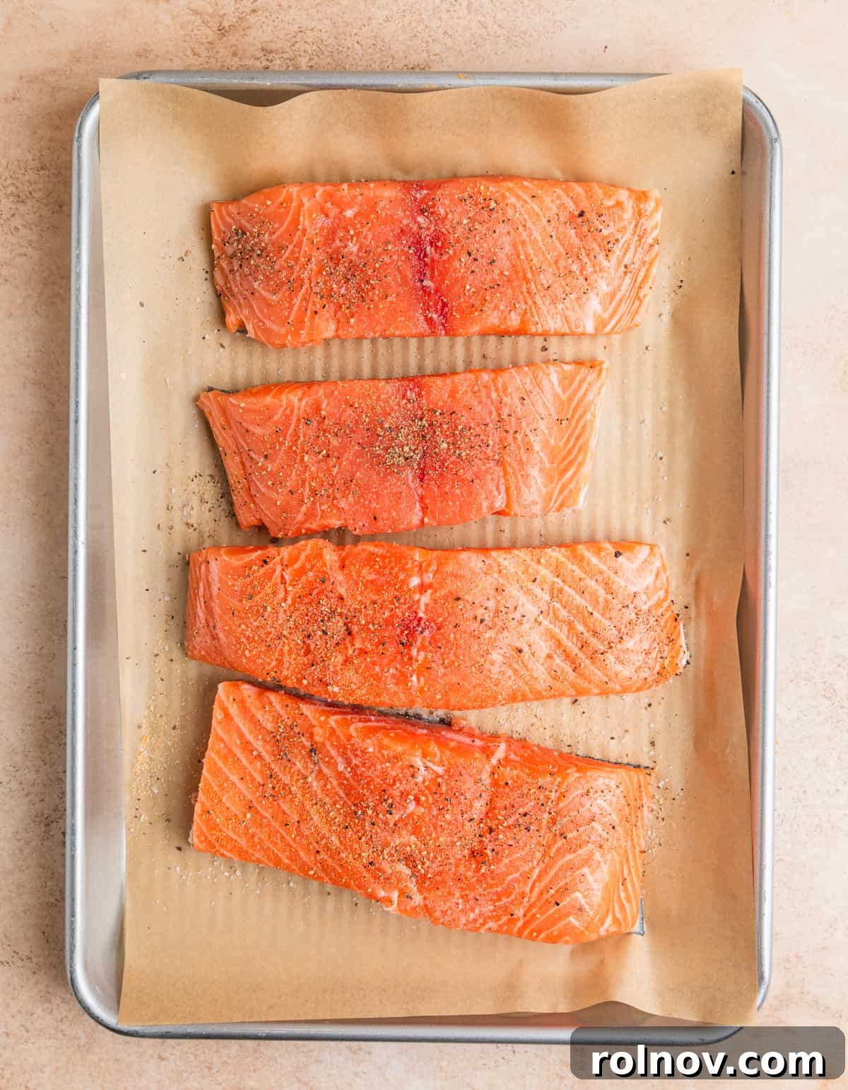 Zesty Lemon Dill Salmon 4 Raw salmon filets on parchment lined pan with seasoning.