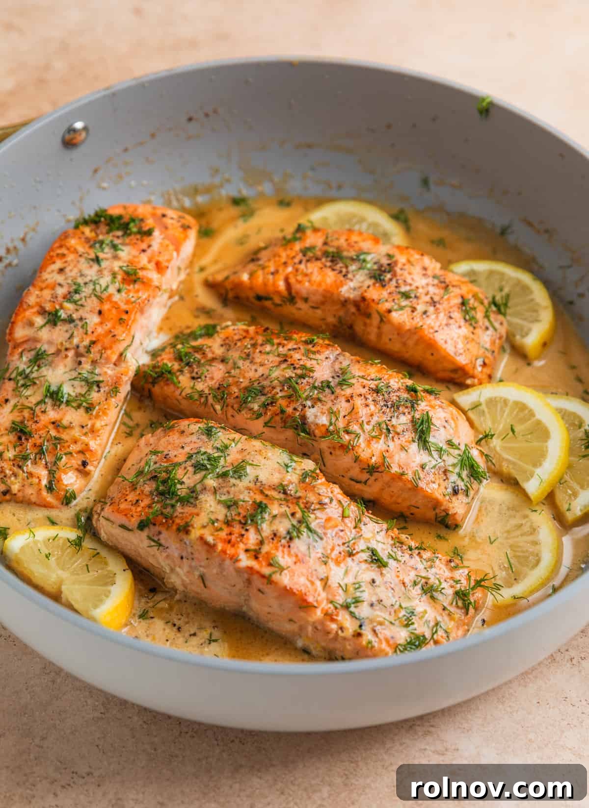 Zesty Lemon Dill Salmon 7 Cooked lemon dill salmon in pan with lemon slices and butter sauce.