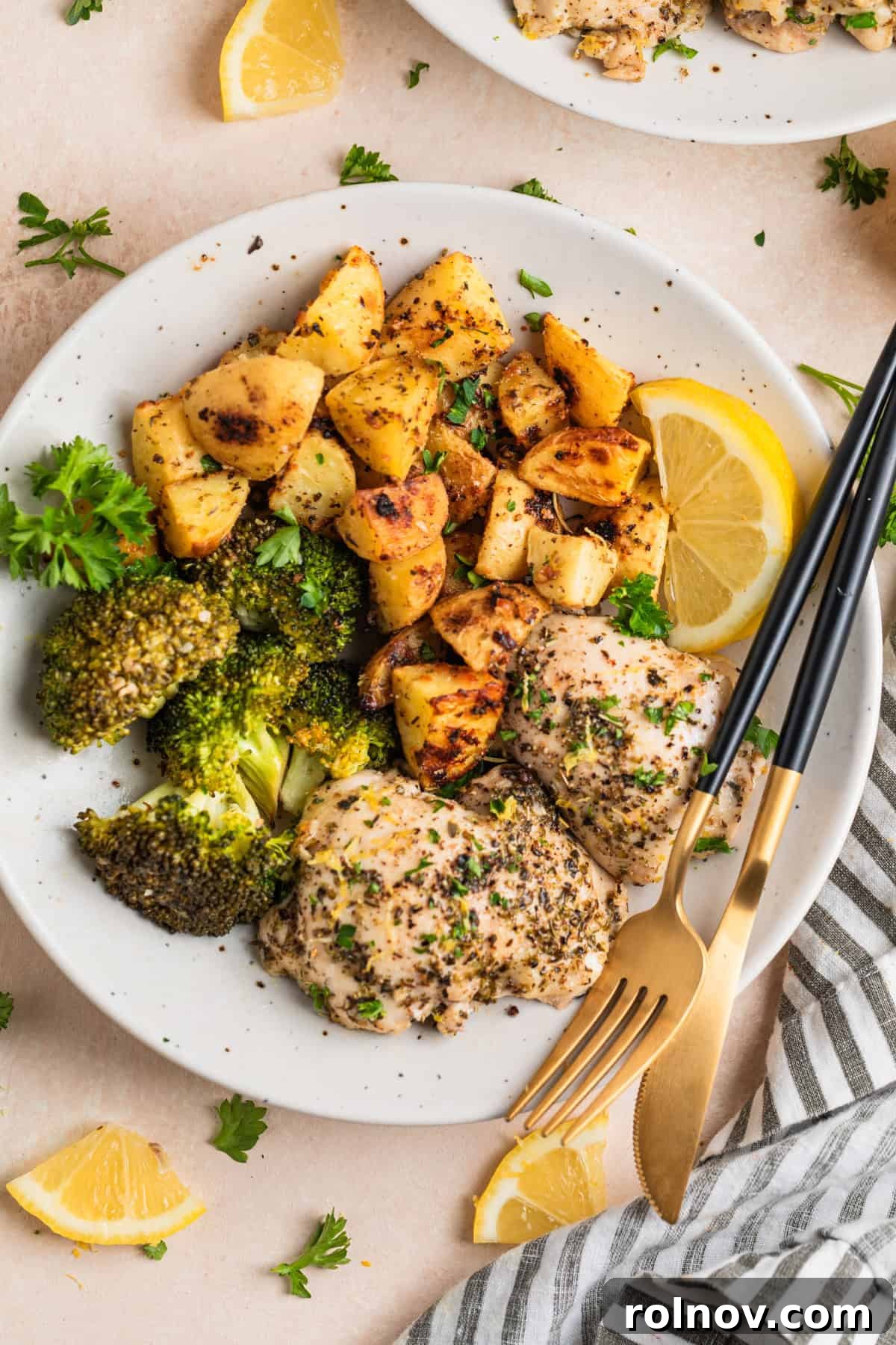 Overhead view of one pan lemon garlic chicken with broccoli and roasted potatoes on white plate.