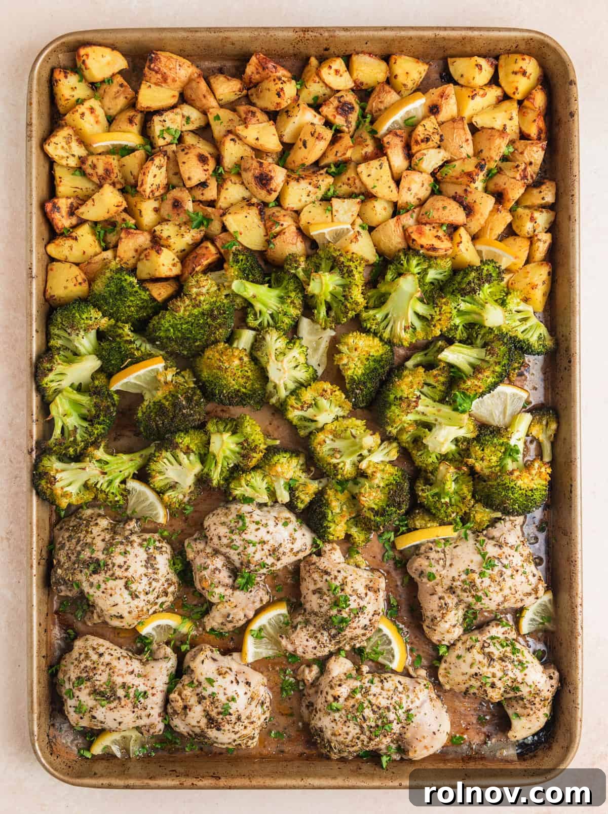 Sheet pan chicken and broccoli with potatoes arranged on baking sheet.