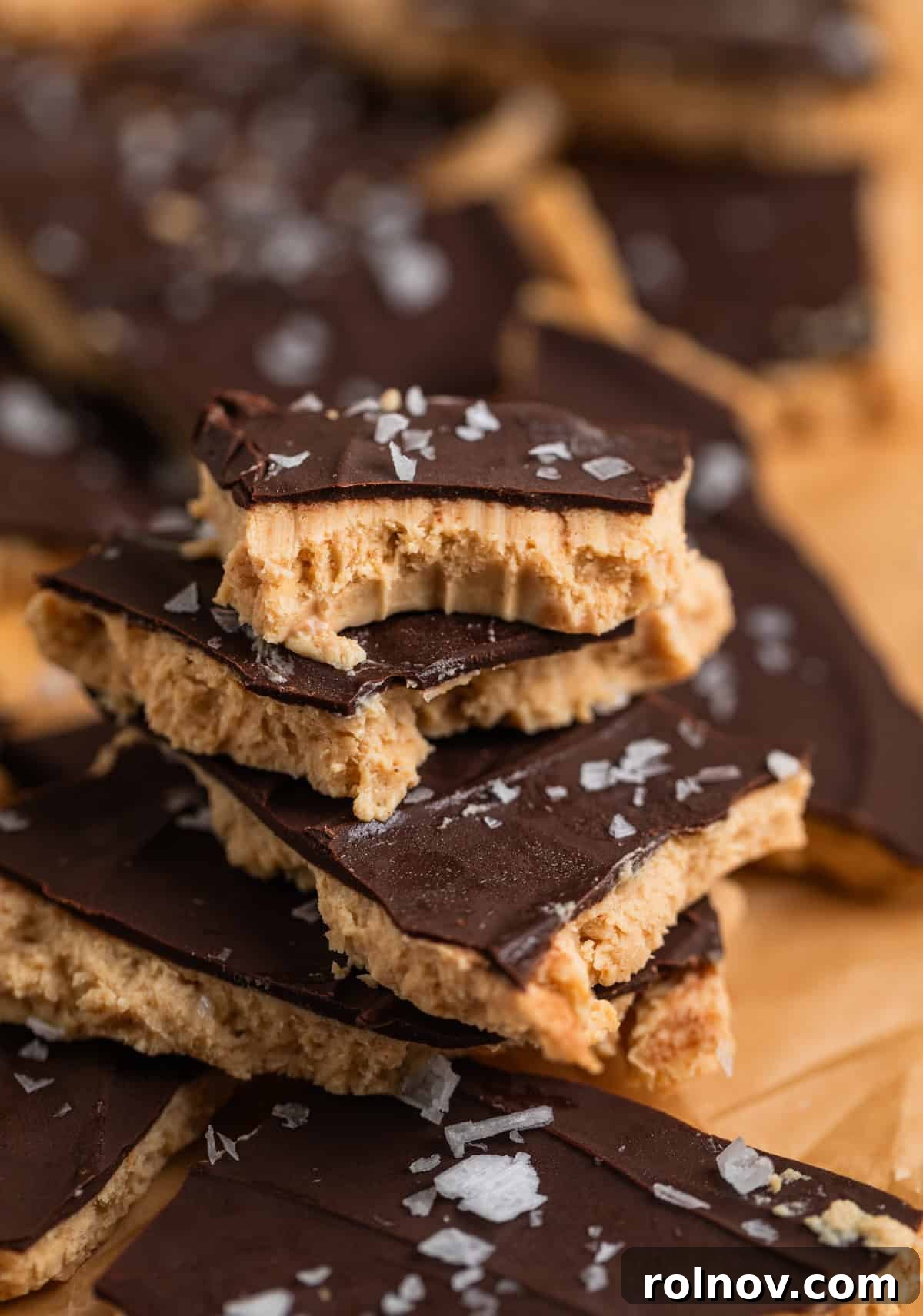 Frozen Greek Yogurt Bites 3 Greek yogurt bark with chocolate and sea salt stacked on each other, with a bite taken out of the top piece, showcasing its delicious layers.