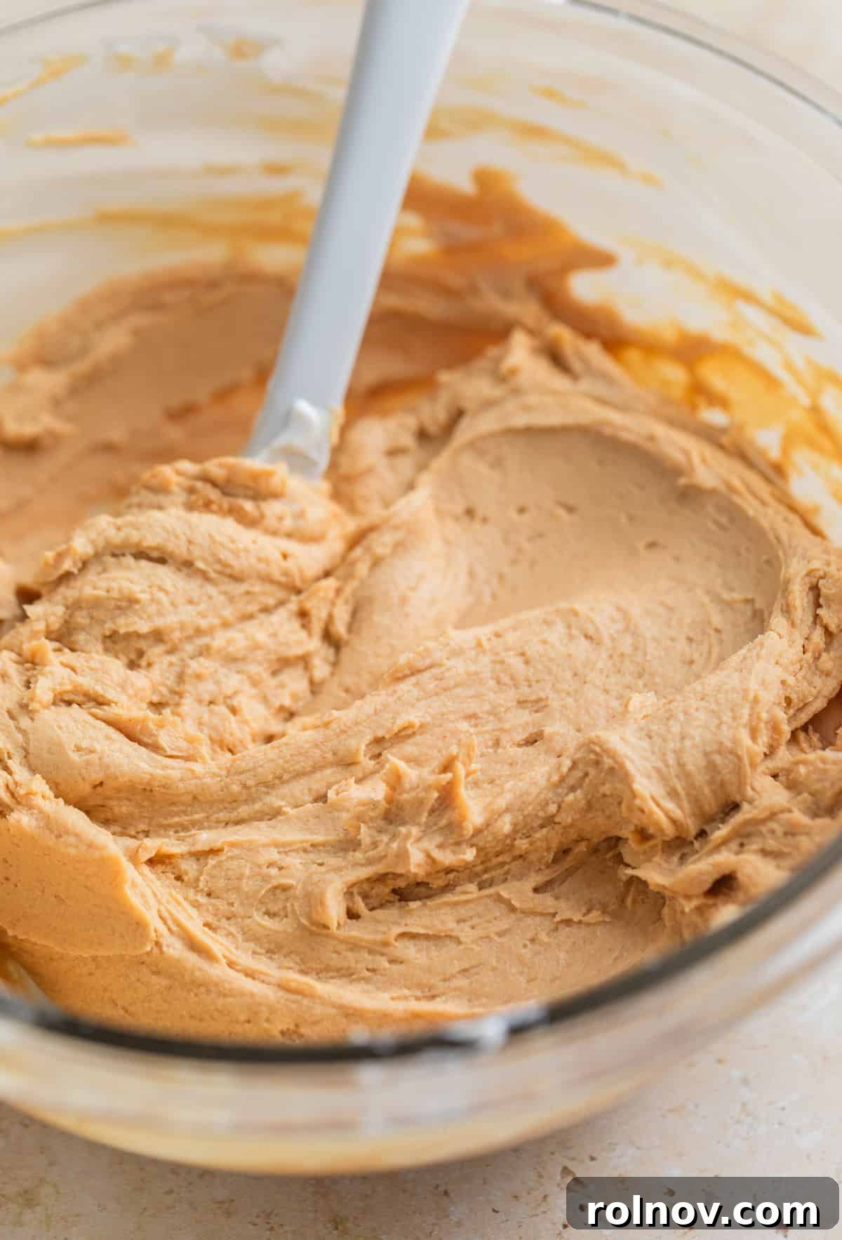 Frozen Greek Yogurt Bites 5 Peanut butter protein yogurt mixture in glass mixing bowl with spoon, showcasing its smooth and creamy consistency.
