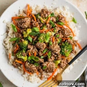Sticky Teriyaki Ground Beef 11 White plate with beef teriyaki served over white rice and topped with chopped green onions and toasted sesame seeds.