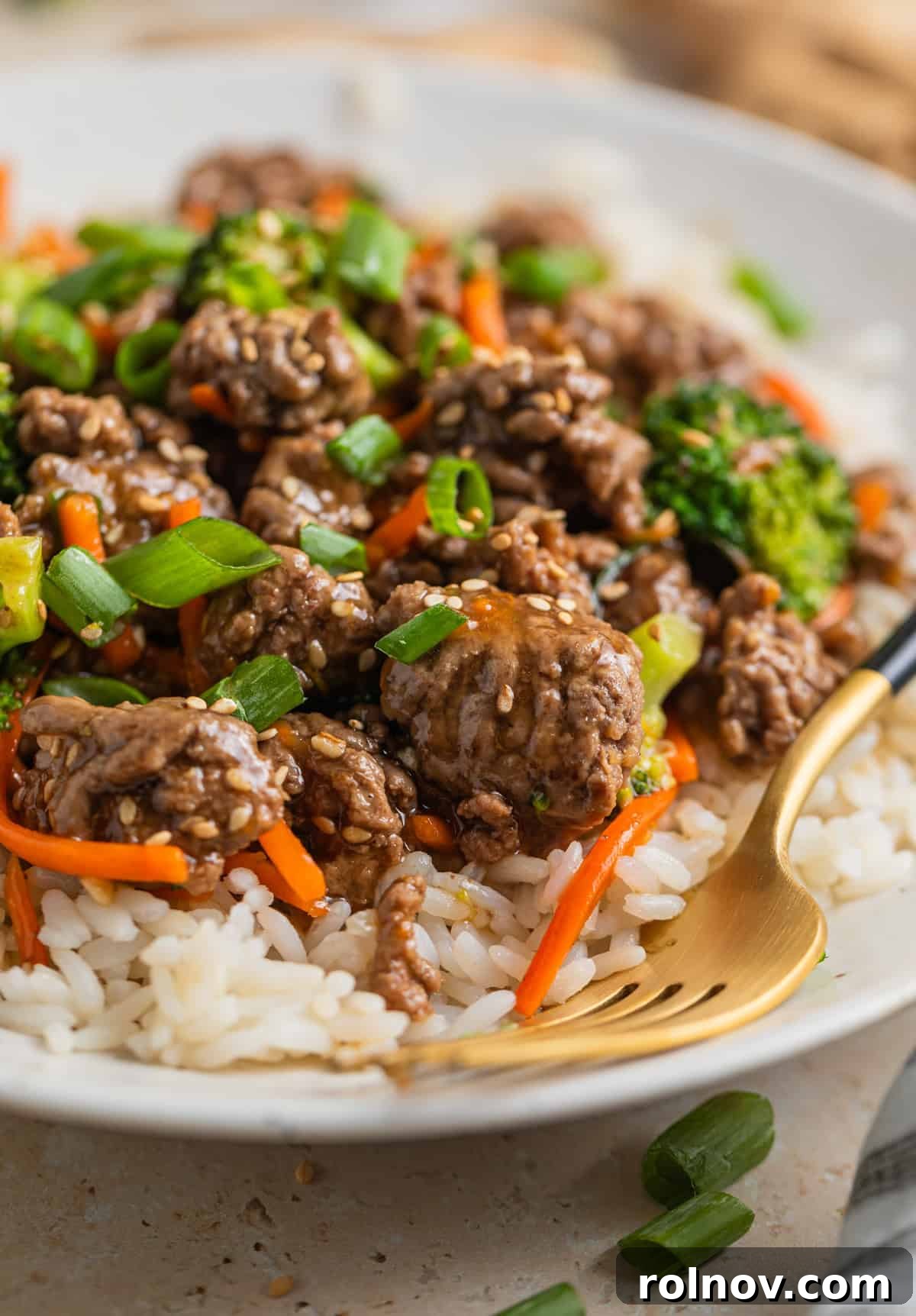Sticky Teriyaki Ground Beef 10 Clay plate with prepared beef stir fry over rice and topped with sesame seeds.
