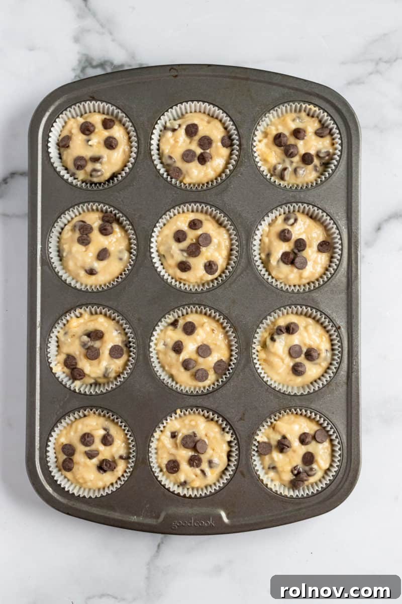 Tropical Banana Chocolate Chip Muffins 8 Coconut banana muffin batter in a muffin tin before baking, topped with extra chocolate chips.