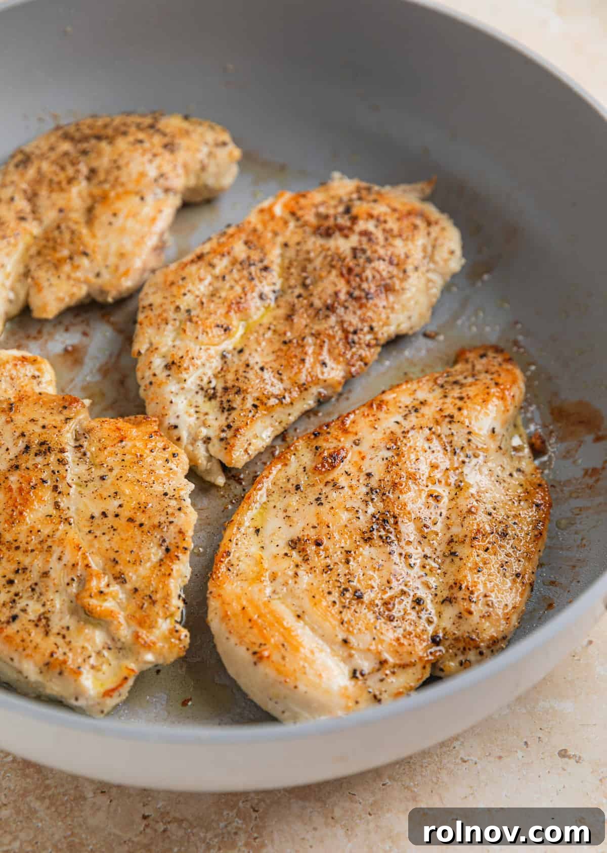 Seared chicken breast in skillet.
