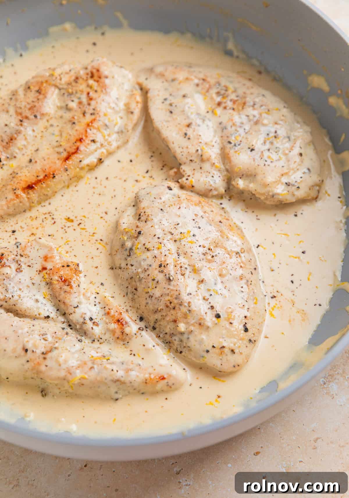 Chicken breasts in creamy lemon sauce in skillet.