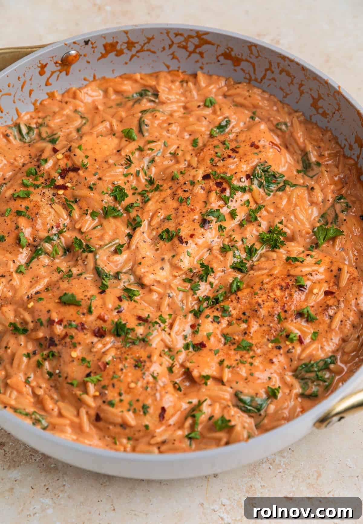 Rich Creamy Chicken Orzo 11 Skillet with creamy orz and chicken topped with chopped parsley.