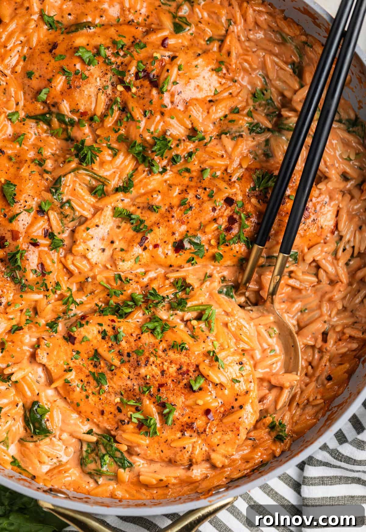 Rich Creamy Chicken Orzo 3 Overhead view of skillet with creamy tomato pasta and chicken topped with parsley.