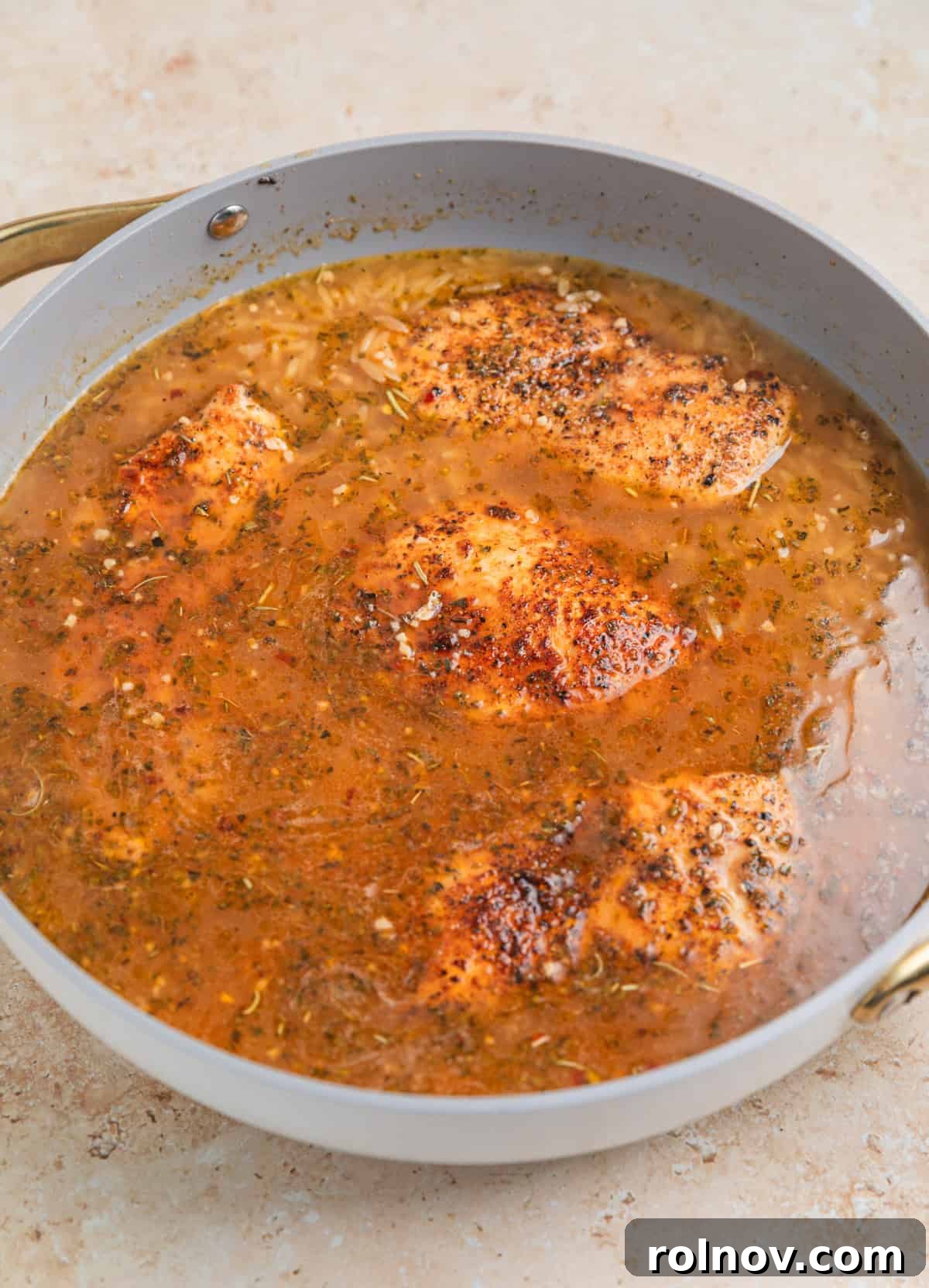 Rich Creamy Chicken Orzo 8 Chicken added to skillet with broth and orzo simmering.