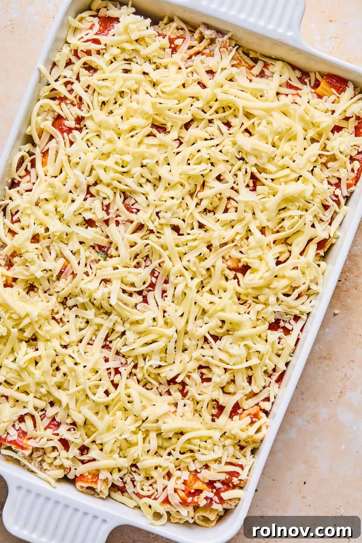 Rustic Italian Sausage Pasta Casserole 13 Shredded mozzarella covering top of pasta bake in pan before cooking.