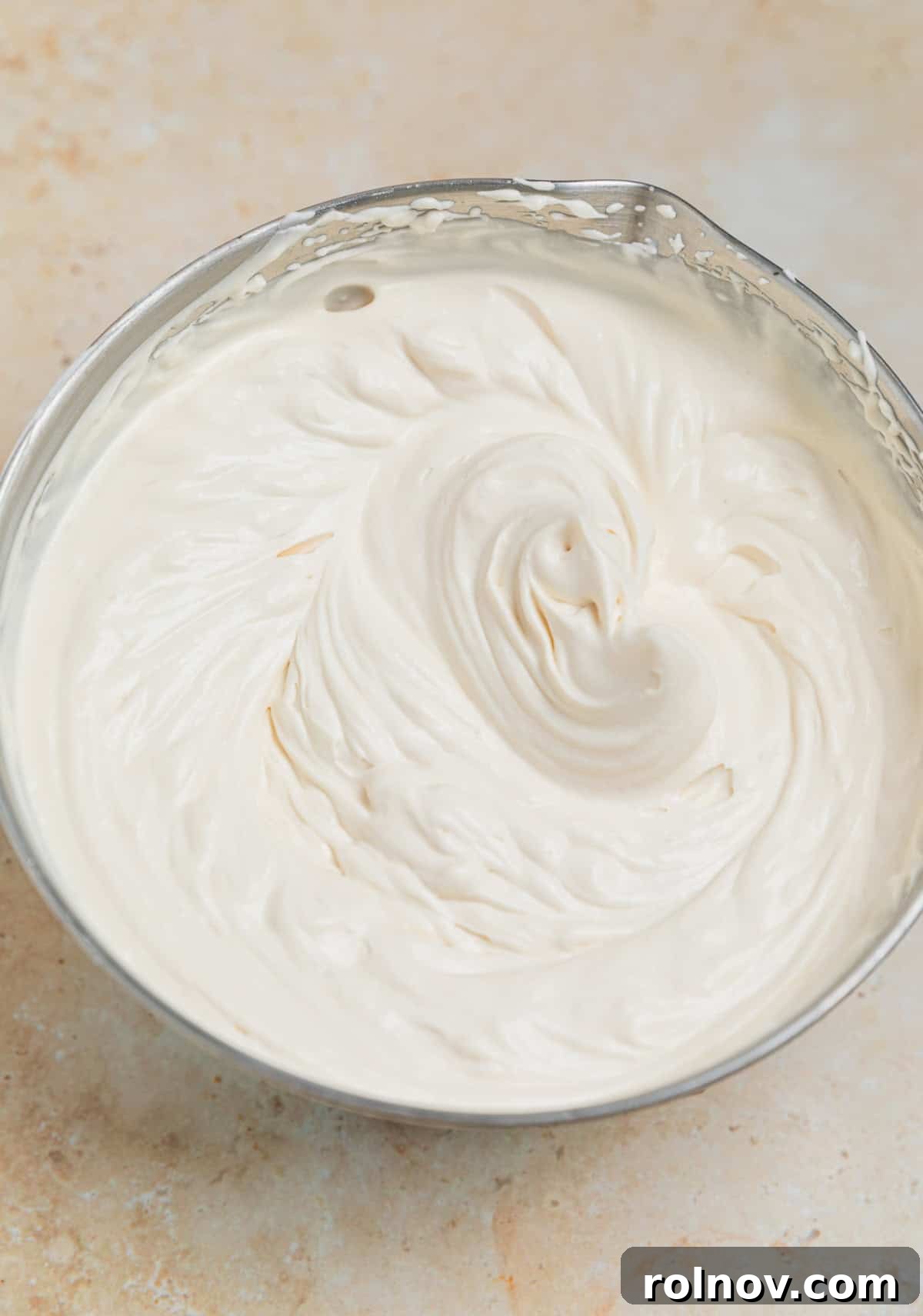 Brown sugar whipped cream beaten to stiff peaks in a small bowl, showing its thick and airy consistency.