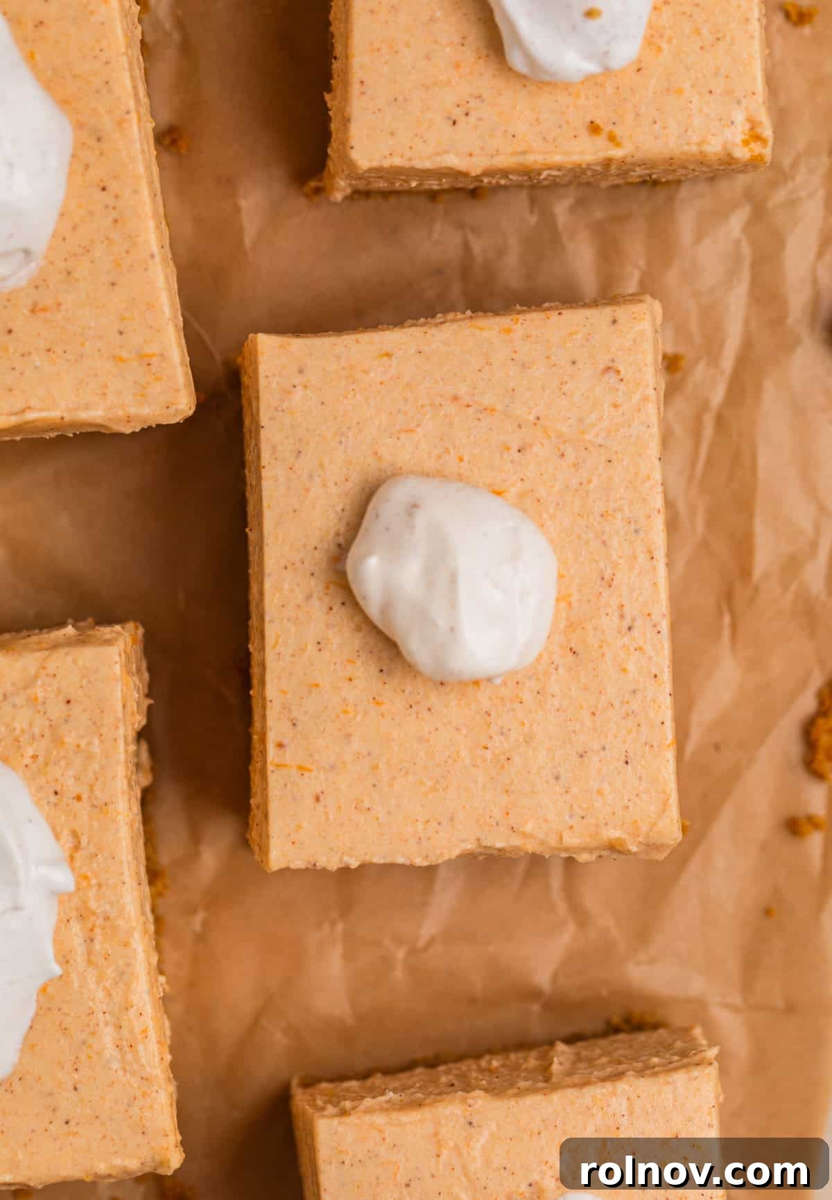Overhead view of slices of pumpkin cheesecake topped with whipped cream and cinnamon dust, ready to be served.