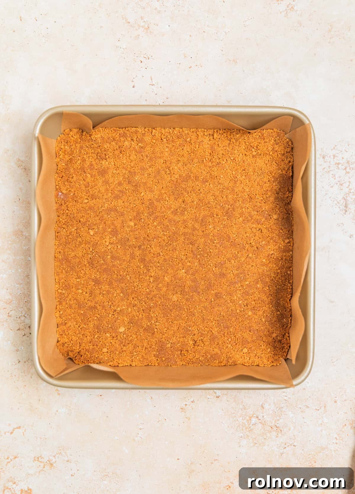 The ginger snap cookie crust firmly pressed into a 9x9 inch square baking pan, lined with parchment paper.