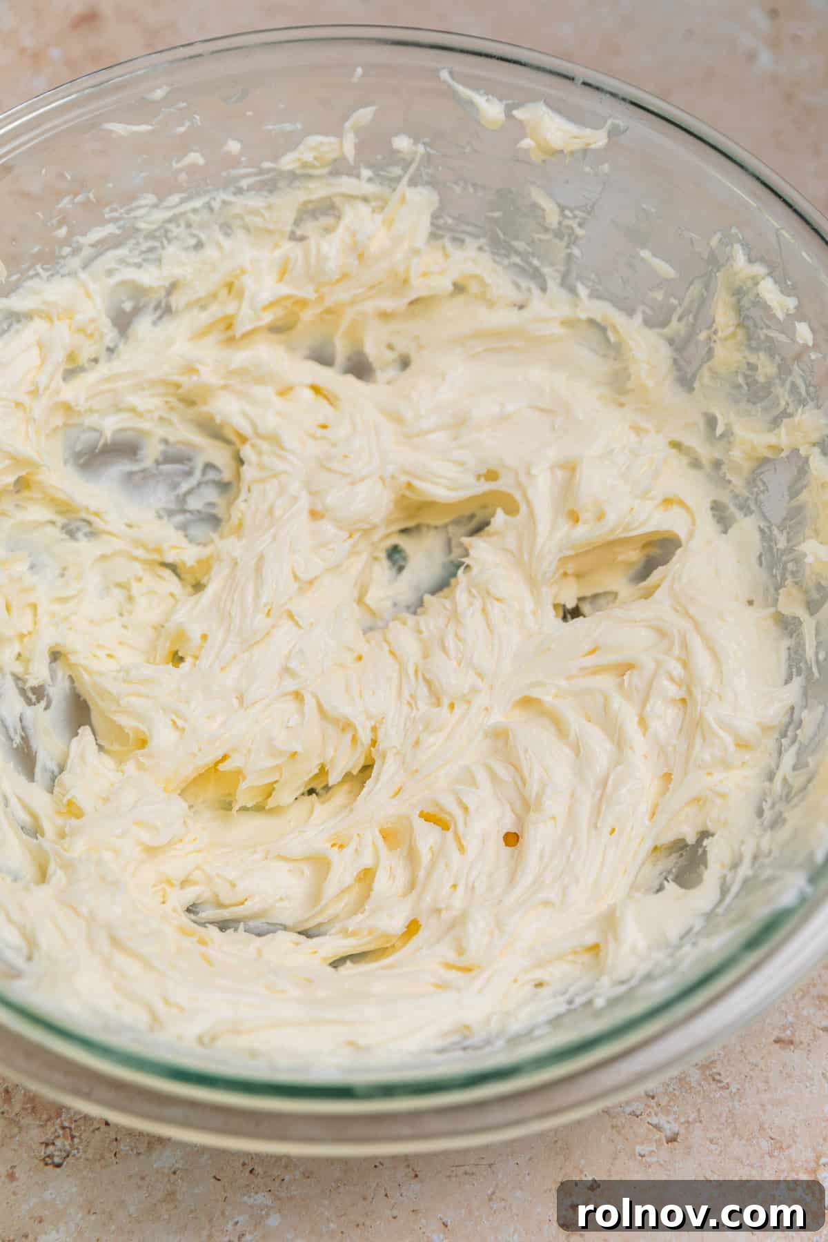 Creamed sugar and softened cream cheese in a large glass mixing bowl, light and fluffy.
