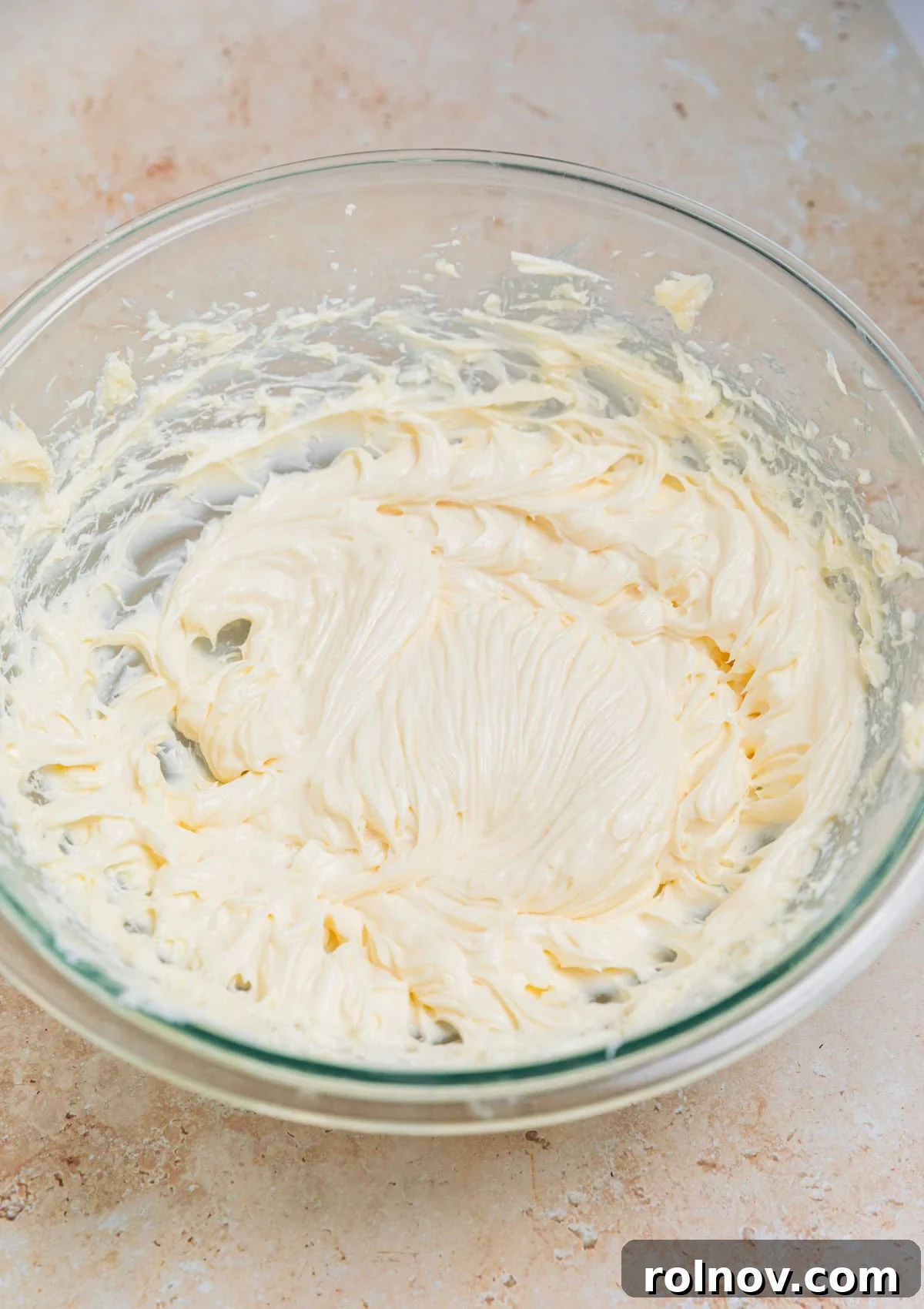 The no bake cheesecake mixture, light in color, in a glass mixing bowl before pumpkin is added.