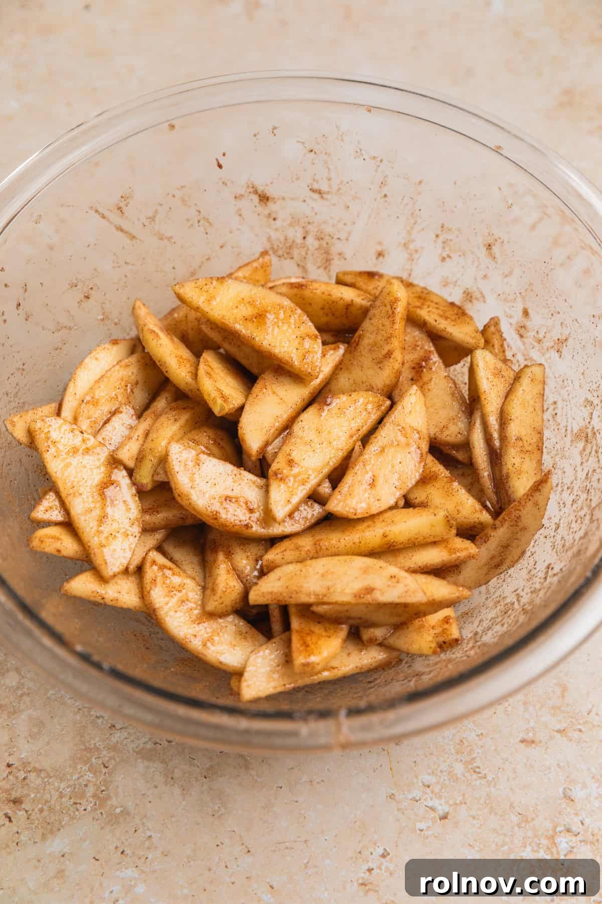 Flaky Apple Delight 4 Apple slices tossed in cinnamon and sugar in glass bowl.