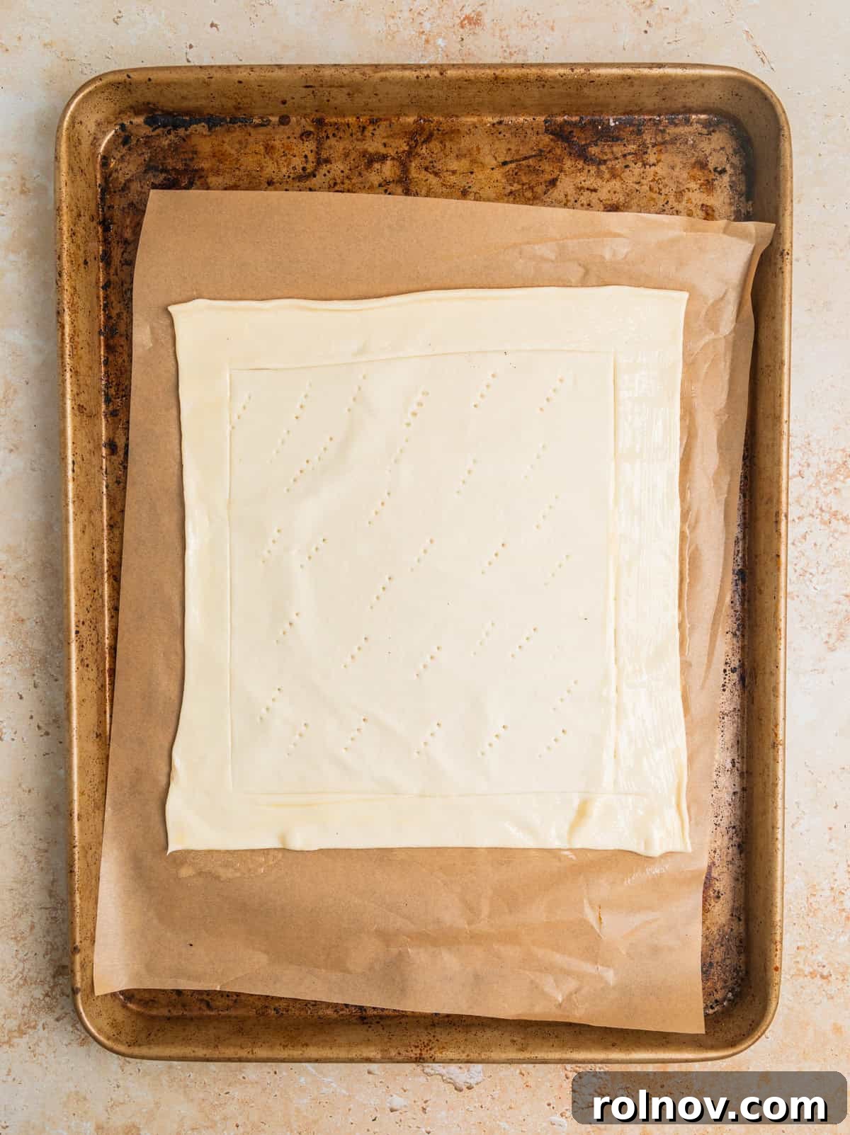Flaky Apple Delight 5 Sheet of puff pastry with edges scored laying on parchment lined sheet pan.