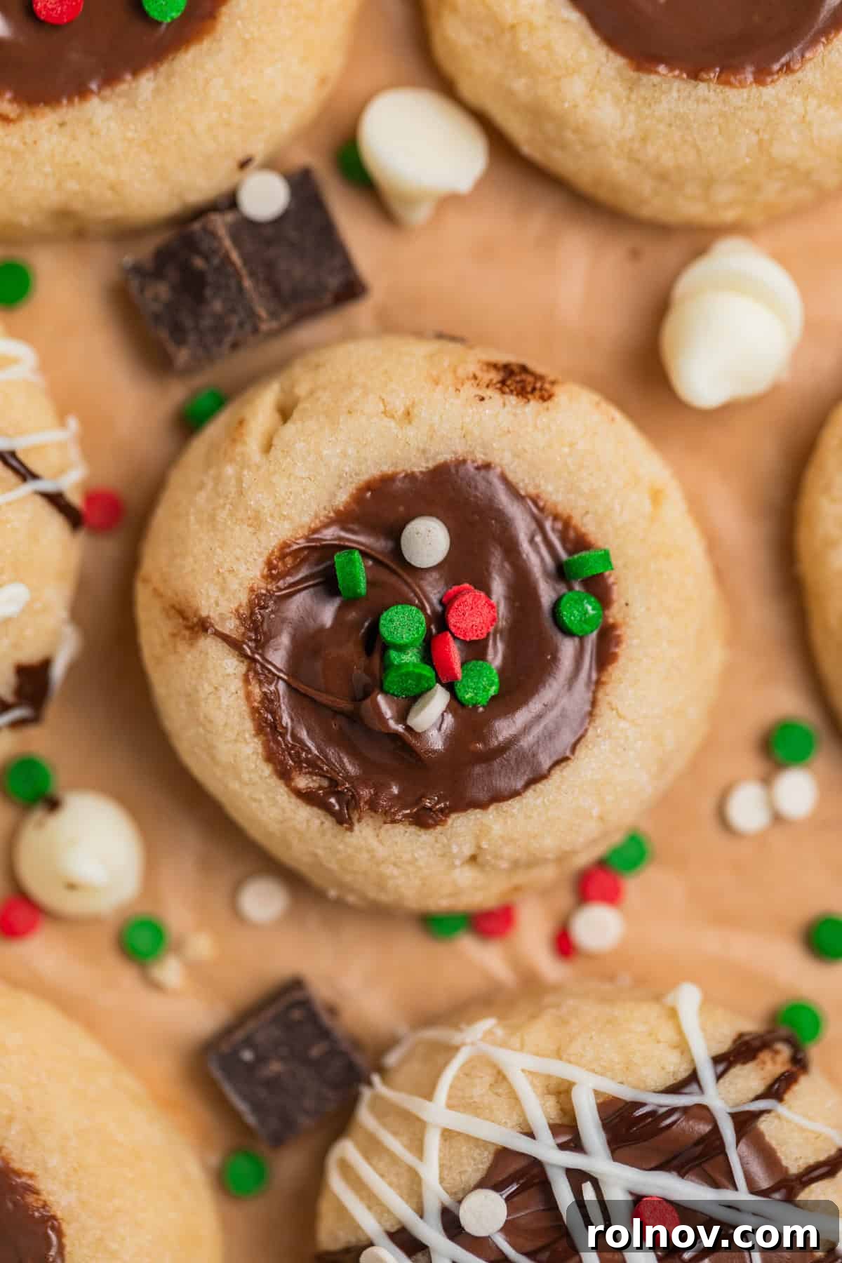 Irresistible Nutella Thumbprints 13 Nutella thumbprint cookies arranged on parchment with red, white and green holiday sprinkles on top.