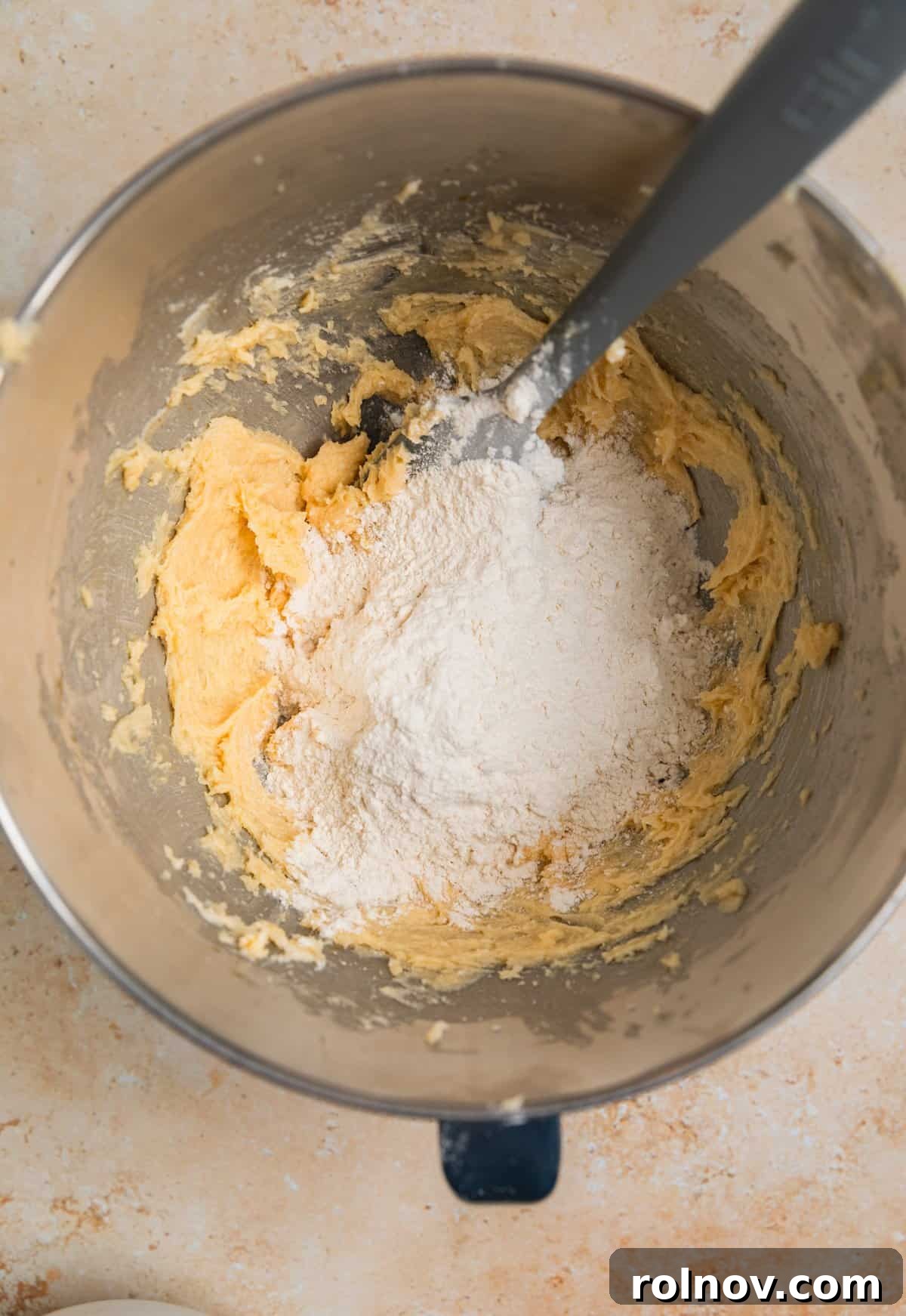 Irresistible Nutella Thumbprints 7 Dry ingredients added to wet ingredients with spatula in bowl.