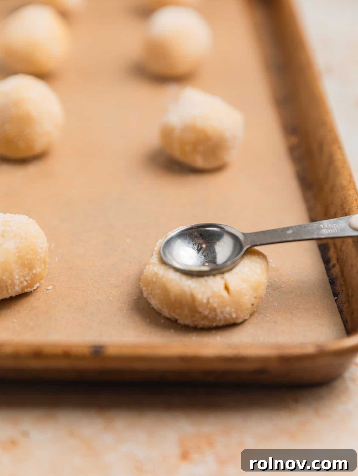 Irresistible Nutella Thumbprints 9 Teaspoon pressing into cookie dough ball to make a thumbprint like impression.