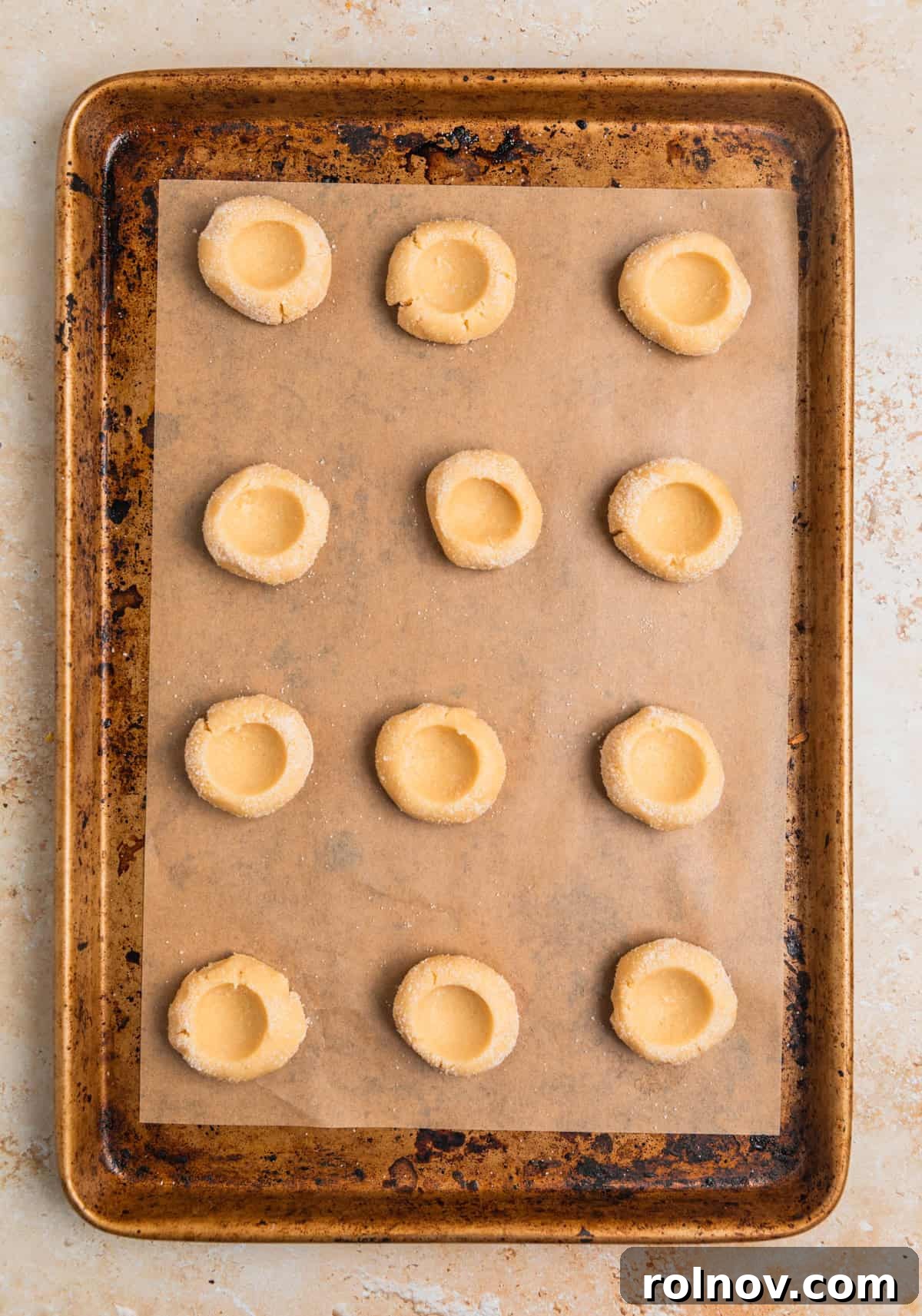 Irresistible Nutella Thumbprints 10 Thumbprint cookie dough arranged on parchment lined cookie sheet.