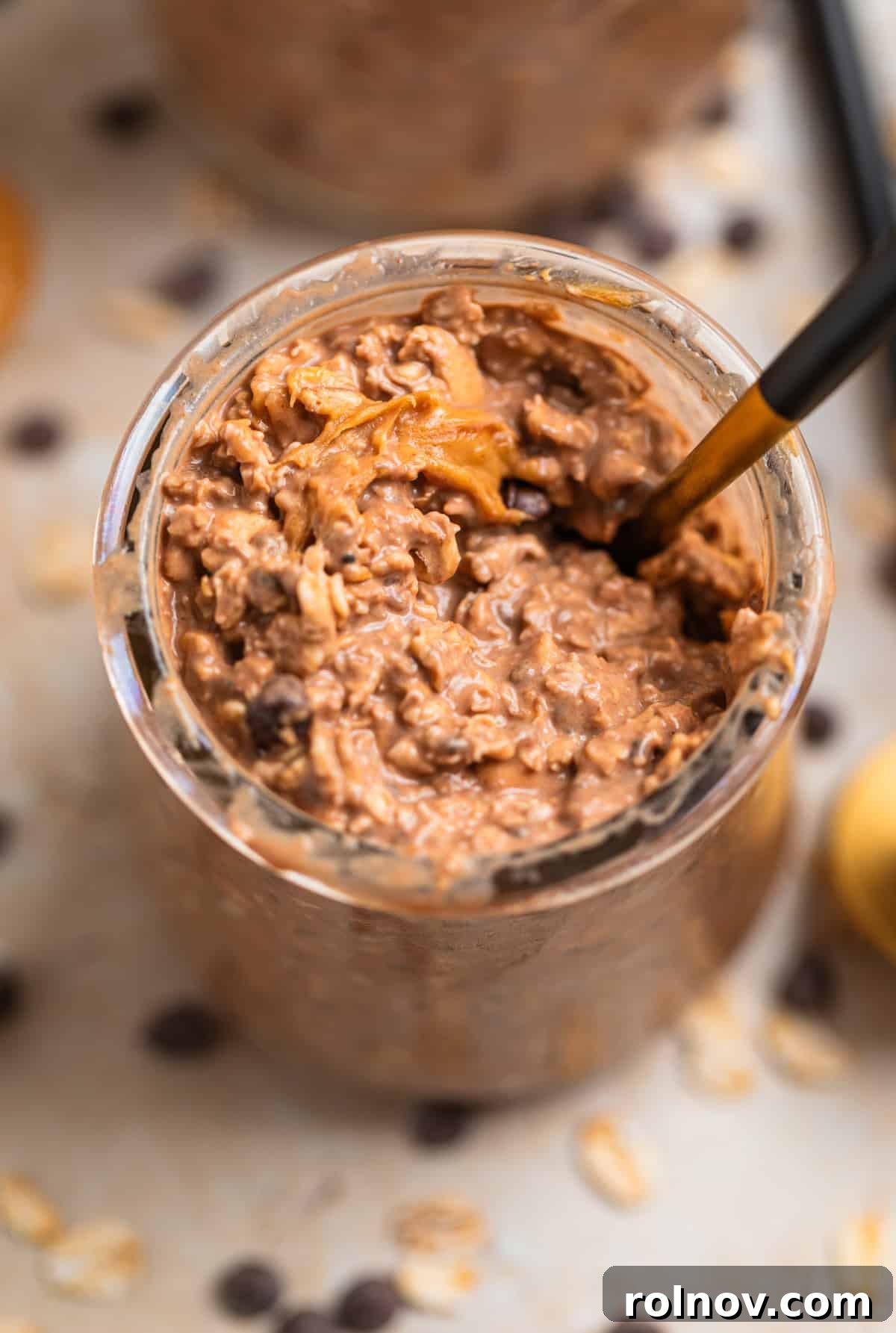 Spoon scooping into chocolate peanut butter overnight oats in glass jar.