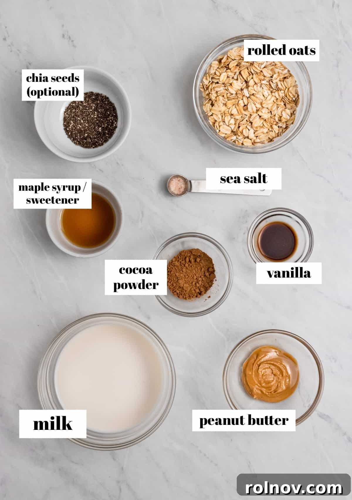 Rolled oats, cocoa powder, maple, and other ingredients in bowls on counter.