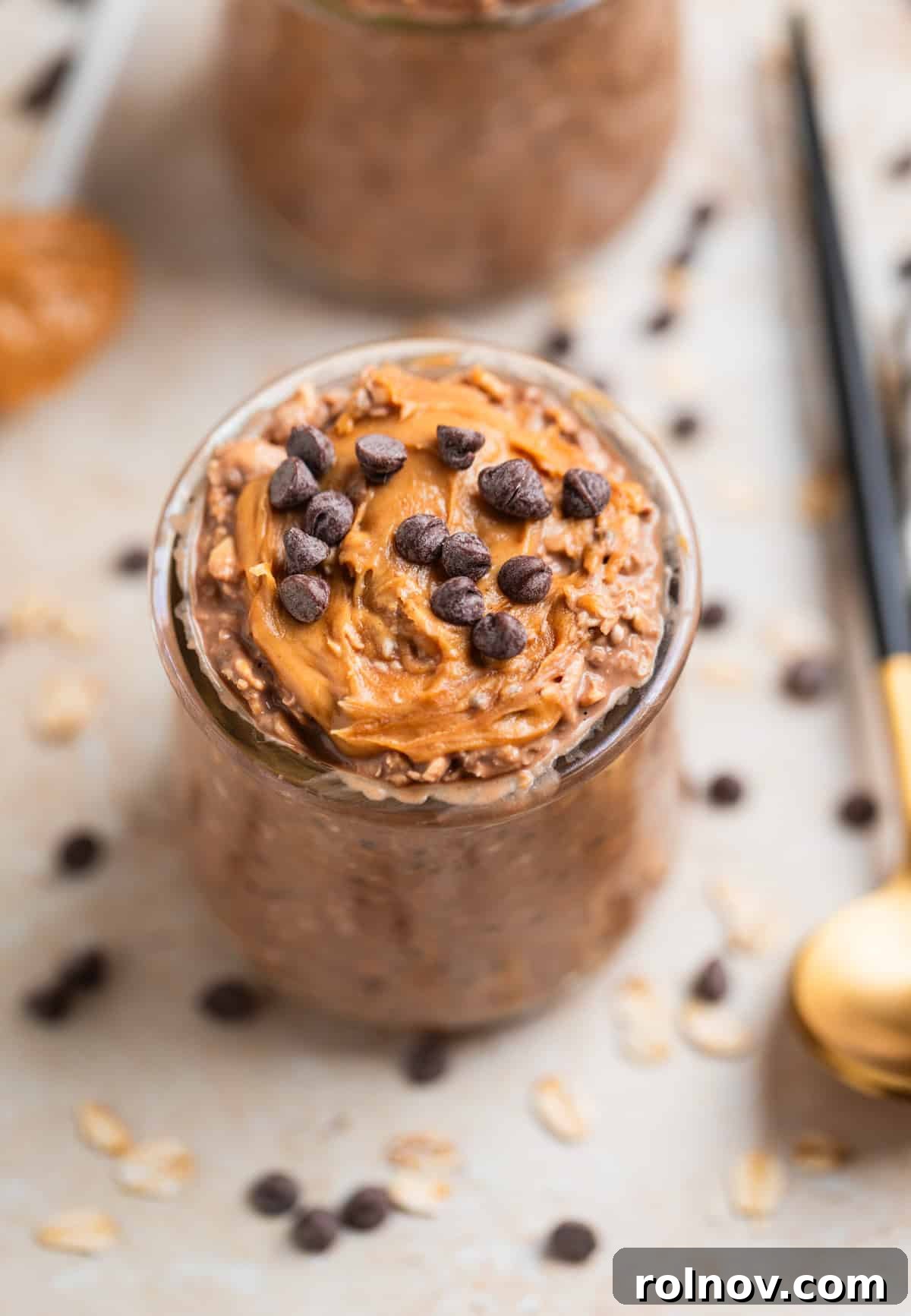 Glass jar with peanut butter topped chocolate overnight oats topped with mini chocolate chips.