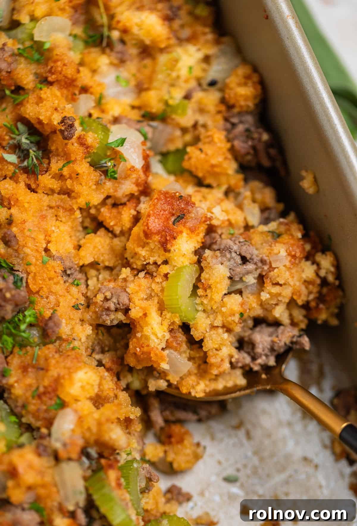 Southern Beef Cornbread Dressing 2 Corn bread and ground beef stuffing in pan with serving spoon scooping into it.