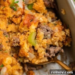 Serving spoon with scoop of cornbread stuffing with ground beef, celery, and fresh herbs.