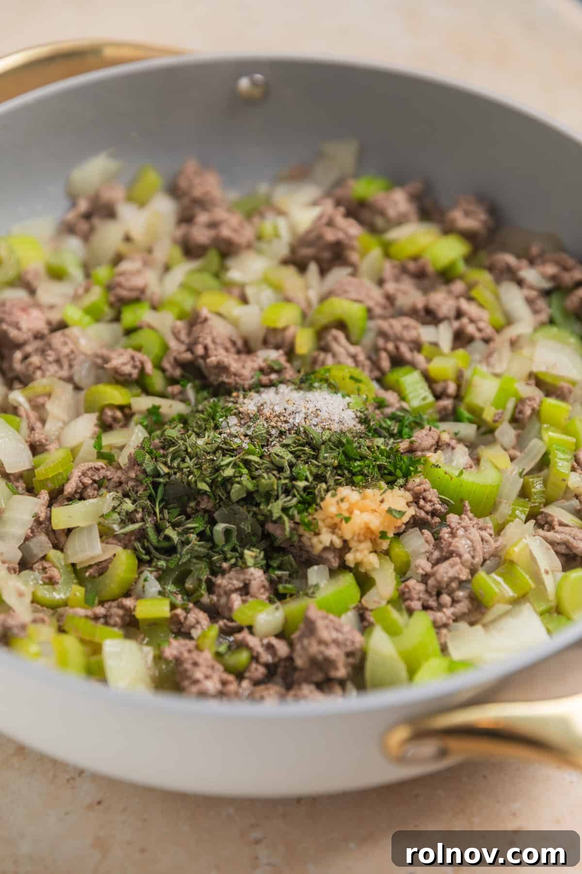 Southern Beef Cornbread Dressing 6 Ground beef browned in skillet with onion and celery and herbs on top.