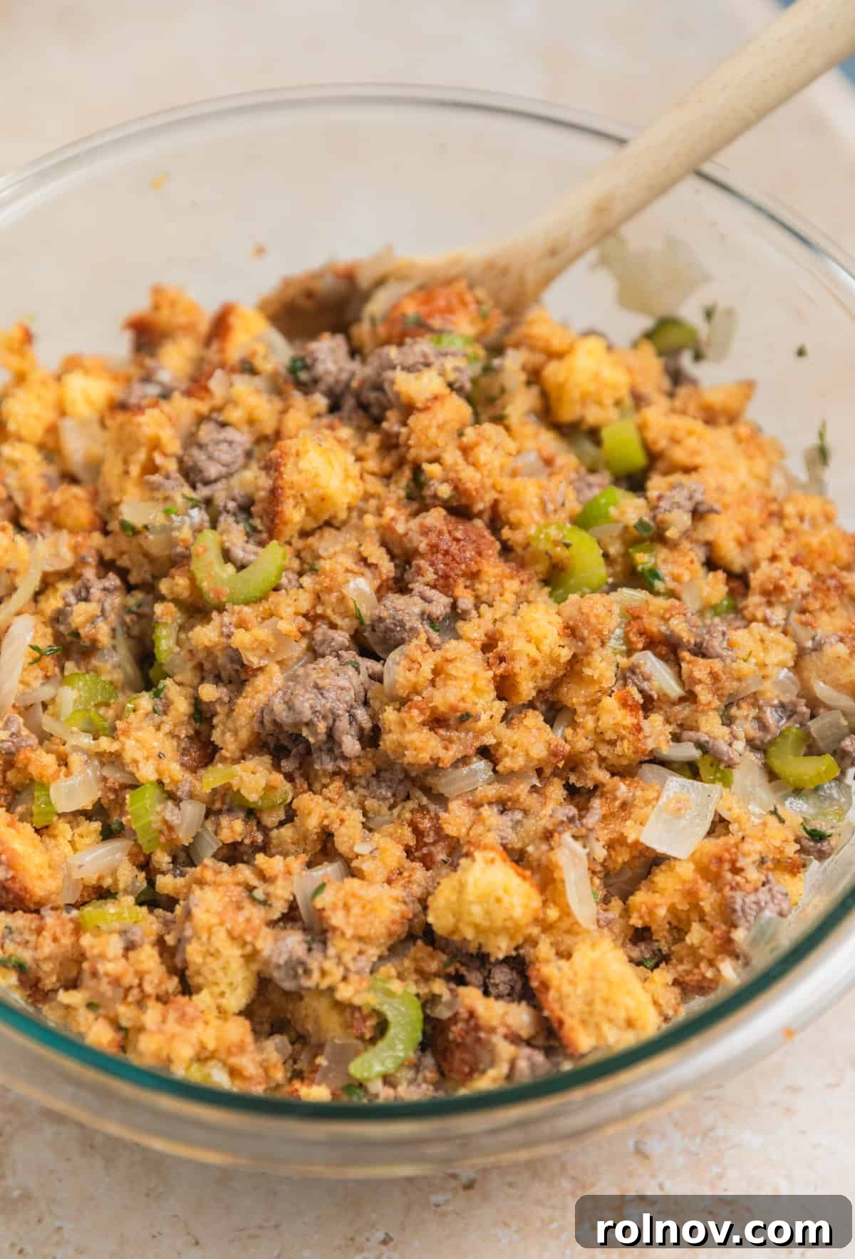 Southern Beef Cornbread Dressing 9 Beef stuffing mixture in large bowl with wooden spoon.