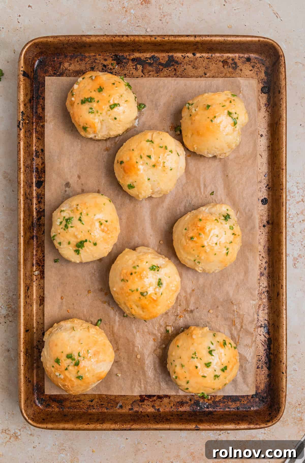 Garlic herb butter brushed on rolls on sheet pan.