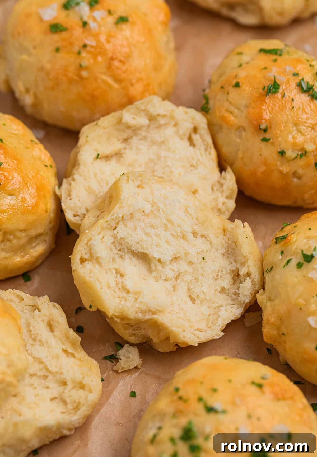 Dinner rolls on parchment with one broken apart to show texture.