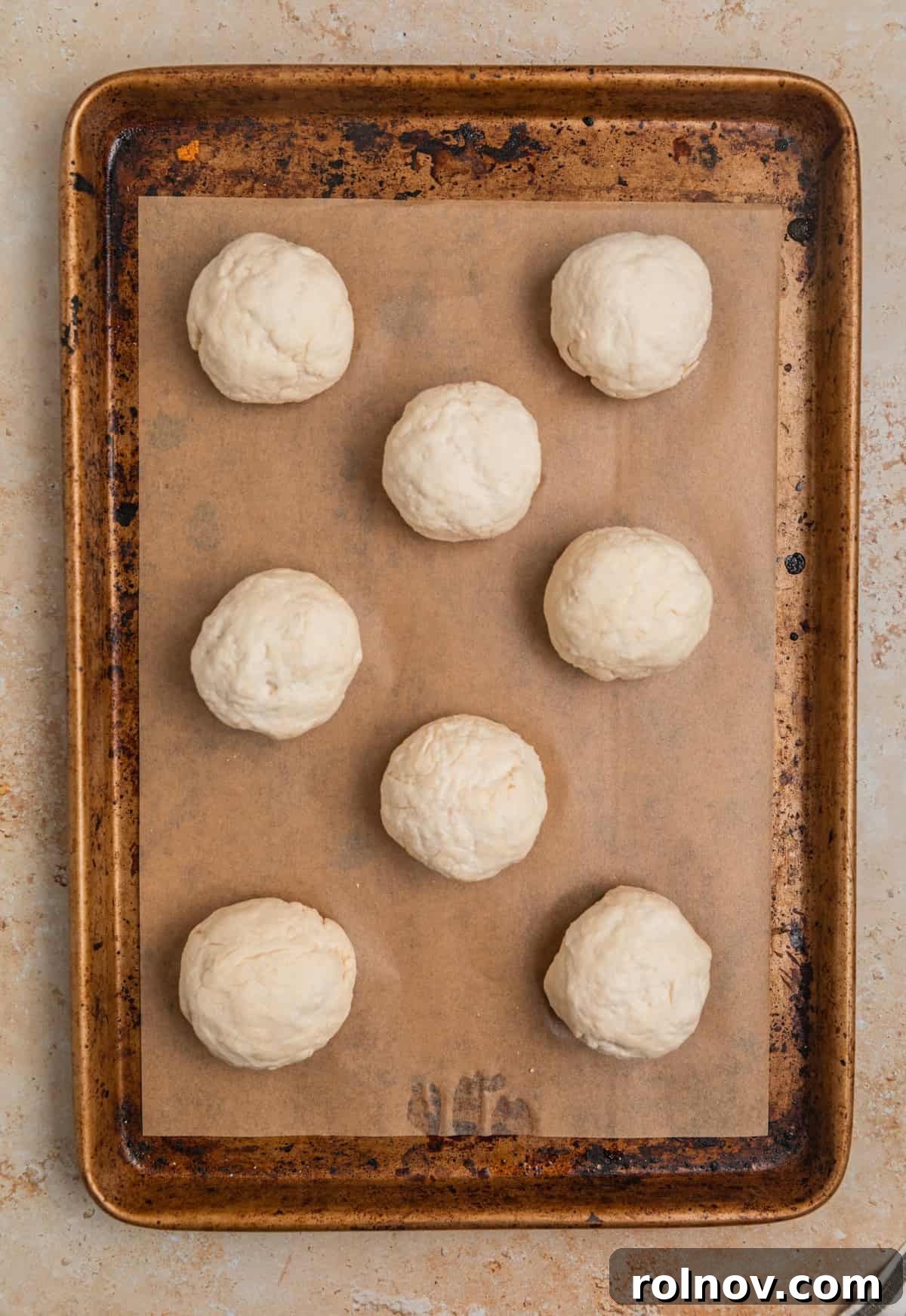 Rolled Greek yogurt dinner rolls on parchment lined sheet pan.