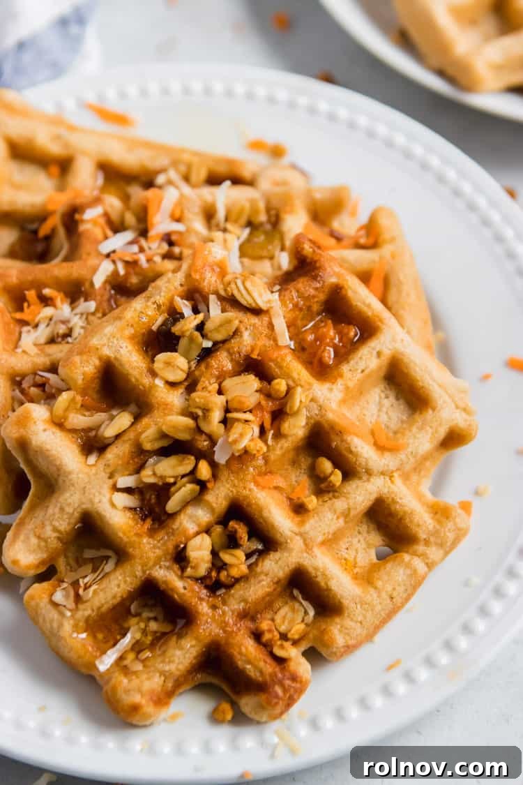 Rustic Carrot Cake Waffles 4 A stack of freshly made Whole Wheat Carrot Cake Waffles, with a side of maple syrup, shredded coconut, and fresh berries, showcasing a vibrant and appealing breakfast.