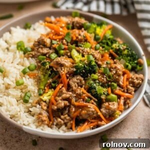 Turkey stir fry served with rice and topped with sesame seeds and green onion.